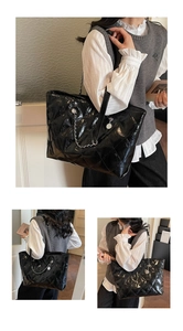 Close-up of black quilted tote bag with glossy finish and silver chain shoulder strap