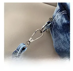Close-up of silver metal swivel clasp and washed blue denim strap texture details