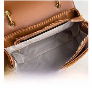 Macro view of brown leather bag interior with grey lining and golden zipper pocket
