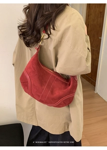 Détail du sac demi-lune en daim rouge avec crochets dorés portés par le modèle