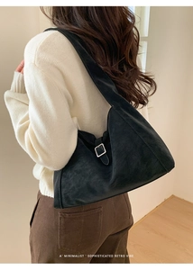 Minimalist black matte leather tote bag with silver buckle worn by a model in a studio
