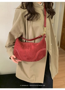 Détail du sac croissant rouge avec surpiqûres blanches sur texture daim doux