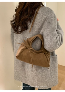 Détail d'un sac à main en daim marron avec nœuds élégants et bandoulière réglable