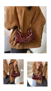 Macro detail of wine red patent leather crescent bag with decorative gold metal chain
