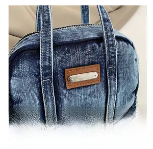Close-up of blue denim handbag featuring brown leather patch and silver metal plate
