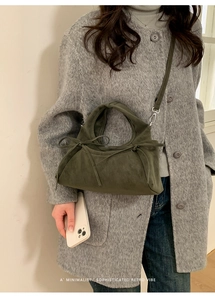 Détail d'un sac à main en daim vert foncé avec nœuds délicats et bandoulière amovible