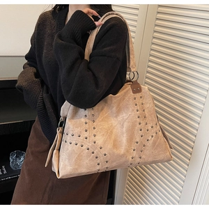 Détail de rivets argentés et de franges sur un grand sac cabas en cuir kaki