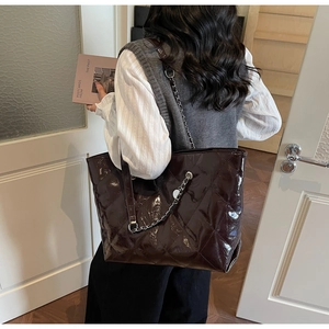 Detail of dark vintage quilted tote bag with glossy finish and silver chain strap