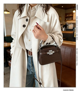 Detailed close-up of brown pebbled leather texture and silver twist lock on the handbag