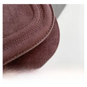 Macro shot of dark brown suede saddle bag showing refined stitching and smooth edge oil
