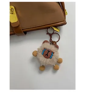 Detailed close-up of a brown plush bear keychain with metallic lobster clasp on a bag