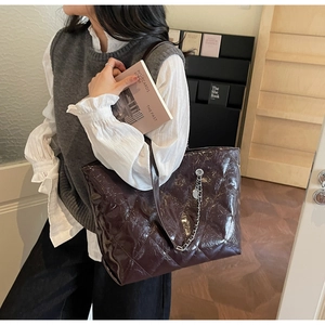 Close-up of quilted dark brown tote bag with high-shine finish and silver chain detail