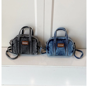 Close-up of vintage washed denim handbags in grey and blue with metal logo plates