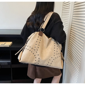 Détail du grand sac cabas crème à rivets porté épaule avec finitions métalliques