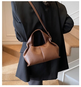 Close-up of brown pebbled leather texture on a stylish pleated dumpling bag shown on model