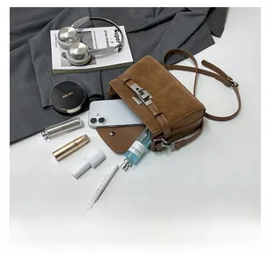 Top view of brown suede crossbody bag showing capacity with phone, perfume, and lipstick