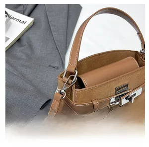 Detail showing brown patchwork suede shoulder bag with silver clasp on a grey blazer