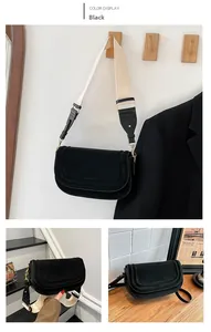 Close-up of black suede saddle bag featuring a wide contrast woven shoulder strap