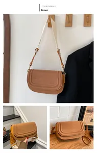 Detail of vintage brown shoulder bag with textured leather and wide fabric strap