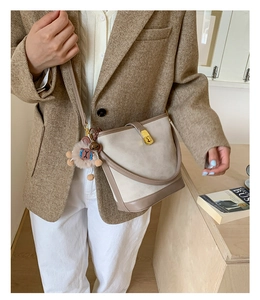 Detail of grey bucket bag with brown leather trim, gold lock and cute bear charm