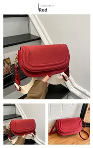Detail of red suede saddle bag with beige fabric strap and gold hardware finish