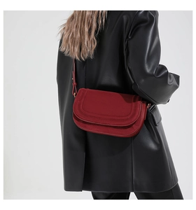 Detail of red leather and suede saddle bag on model with long shoulder strap