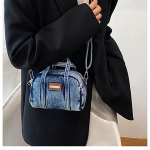 Close-up of blue denim mini crossbody bag with silver hardware and brown leather patch detail