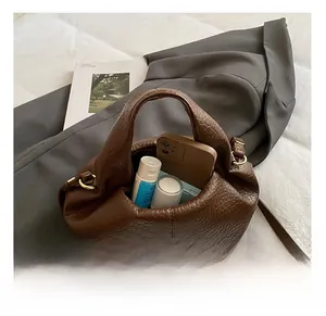 Detail view of large interior capacity and litchi texture on dark brown shoulder bag