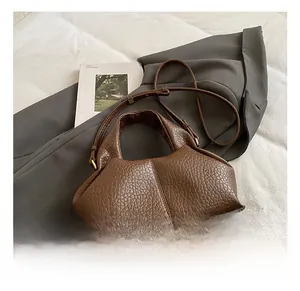 Detailed close-up of brown pebbled leather cloud bag with shoulder strap and handle
