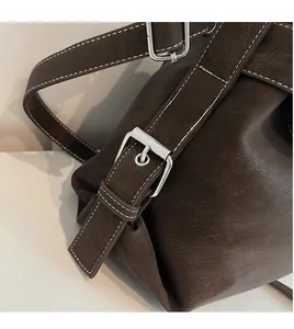 Detailed view of brown lychee leather tote with white contrast stitching and silver buckle