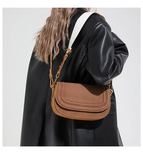 Rear view of model wearing brown suede saddle bag with fine stitching on black jacket