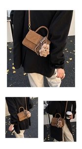 Detail of coffee brown suede crossbody bag with teddy bear charm on autumn street