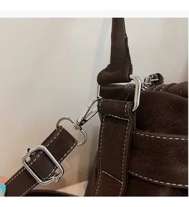 Detail of silver hardware hooks and stitching on a dark brown vintage leather tote bag