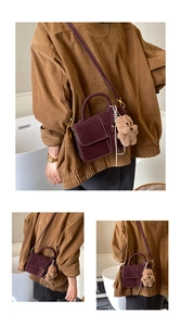 Detail of burgundy suede tote with white contrast stitching and plush puppy charm