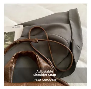 Detail of adjustable shoulder strap and textured leather handle on brown cloud bag