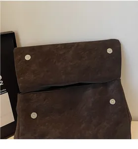 Detail of silver magnetic snaps on retro dark brown faux leather bag with vintage texture