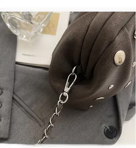 Detail of dark brown pleated clutch with silver rivets and metal chain strap decoration