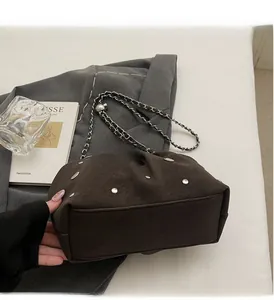 Detail of dark brown rivet cloud bag with chain strap and soft pleated PU leather texture