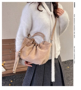 Detail of beige suede drawstring bucket bag with metal handle and mini coin purse pouch