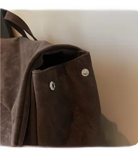Detail of dark brown leather backpack showing side folding structure and silver metal snaps
