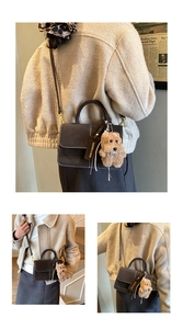 Detail view of brown vintage square bag with contrast stitching and plush dog charm