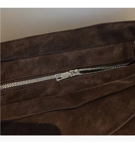 Detailed close-up of smooth silver metal zipper on dark brown faux suede backpack