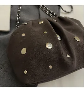 Detail of vintage brown textured leather handbag with polished metal studs and chain strap