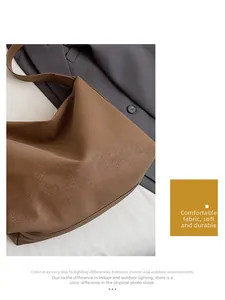 Detail view of smooth brown tote bag leather texture on a grey blazer background