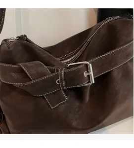 Detail of dark brown lychee leather handbag with silver buckle and white stitching