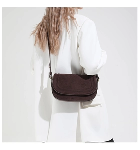 Detail view of a dark coffee suede crossbody bag with thin leather strap and flap design