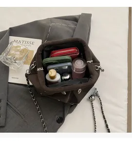 Detail view of the spacious brown suede bag interior with phones and cosmetics