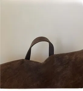 Detail of a dark brown leather backpack showing a textured handle and stitching