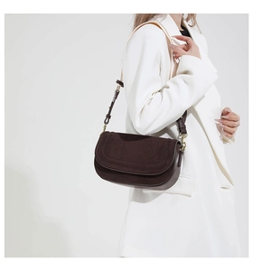 Detail of dark brown shoulder bag with metal buckle and contrast stitching on textured leather