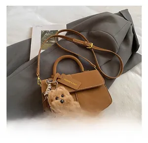 Caramel brown leather handbag detail with adjustable strap and cute plush dog charm